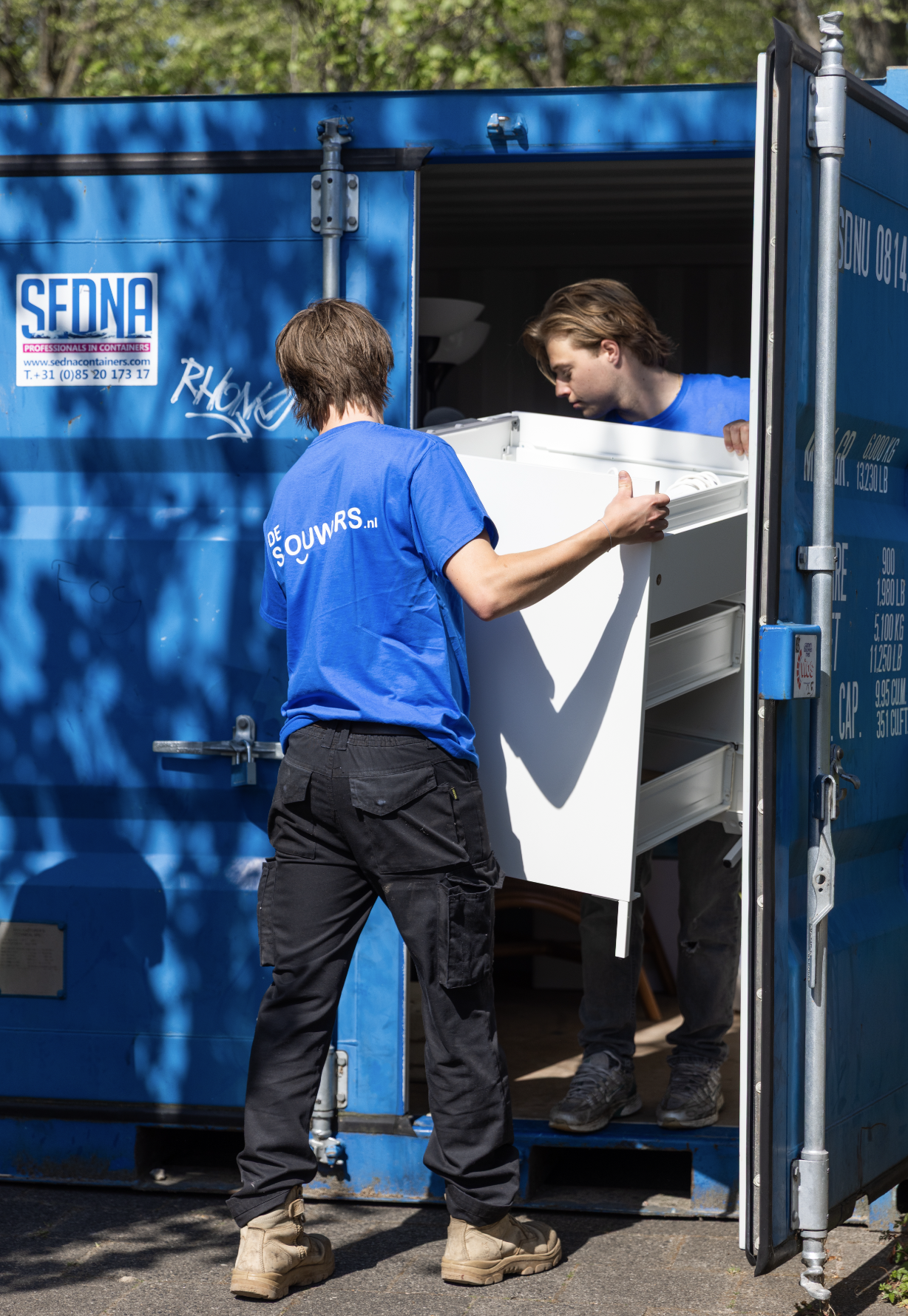 Sjouwers helpen met container lossen